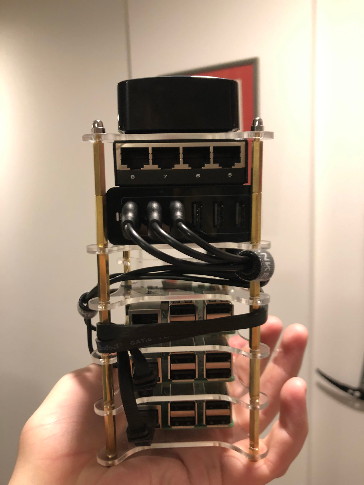 four raspberry pis and a router stacked and networked together in the hand of an angel